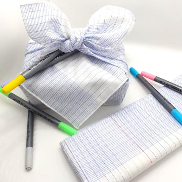 Paquet cadeau en tissu aux motifs lignes de cahier. Avec des feutres pour textile.