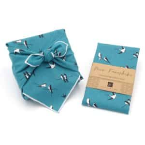 Emballage cadeau en tissu bleu avec motif oiseau.