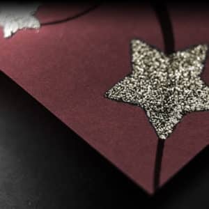Papier cadeau de Noël de couleur Bordeaux avec motif d'étoiles dorées en relief.