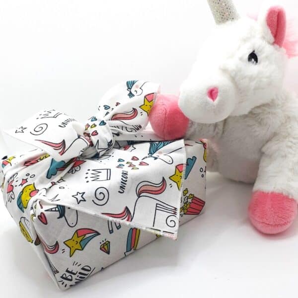 Un paquet cadeau réalisé avec un tissu furoshiki au motif de licorne. Parfait pour offrir un cadeau à une petite fille.